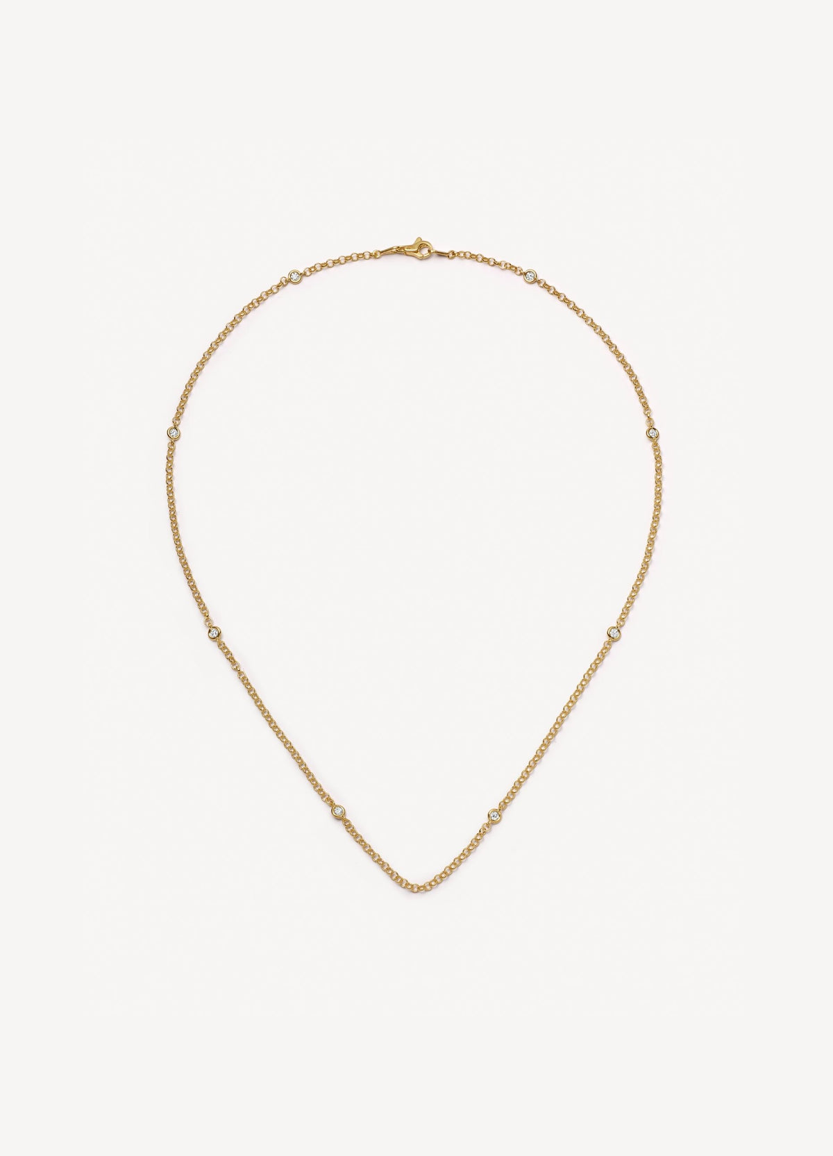 A delicate yellow gold chain necklace with evenly spaced diamond details, displayed on a clean, light off-white background.