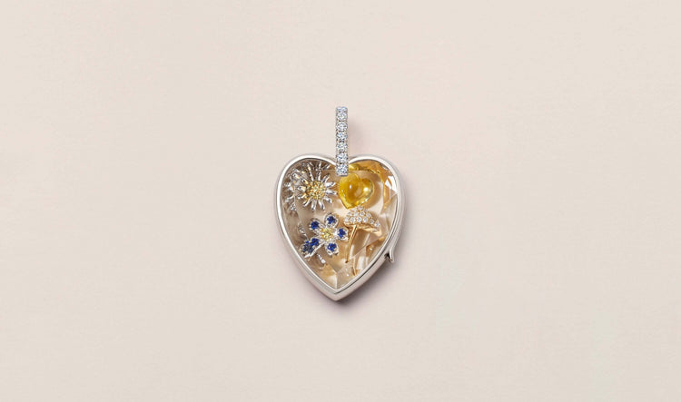 White gold heart shaped Amate locket with crystal facade and diamond bell styled with a flower charm, daisy charm, yellow heart and a mushroom charm. 