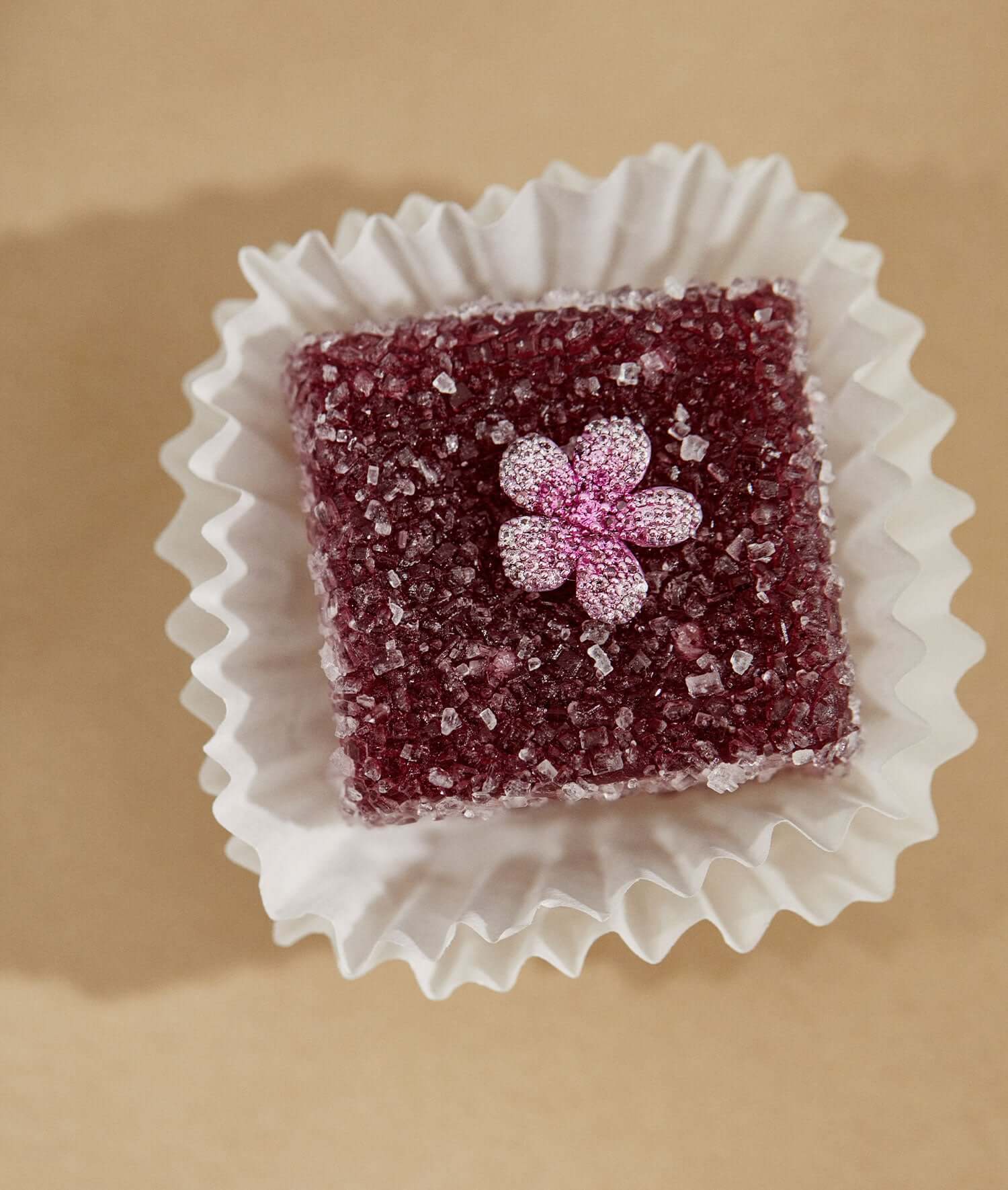 Blooming blossom flower sapphire charm on top of a maroon fruit paste square.