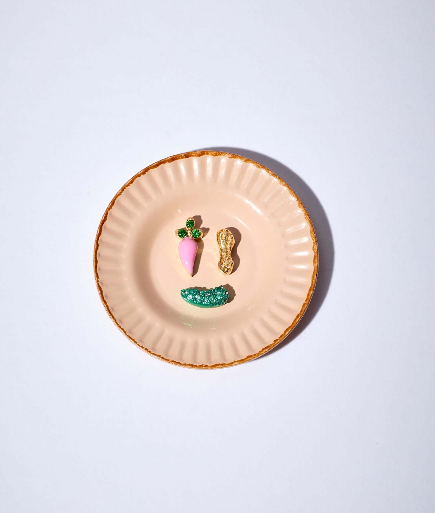 a carrot charm, a peanut charm, a pickle charm on a small dish plate.
