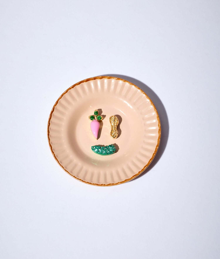 a carrot charm, a peanut charm, a pickle charm on a small dish plate.