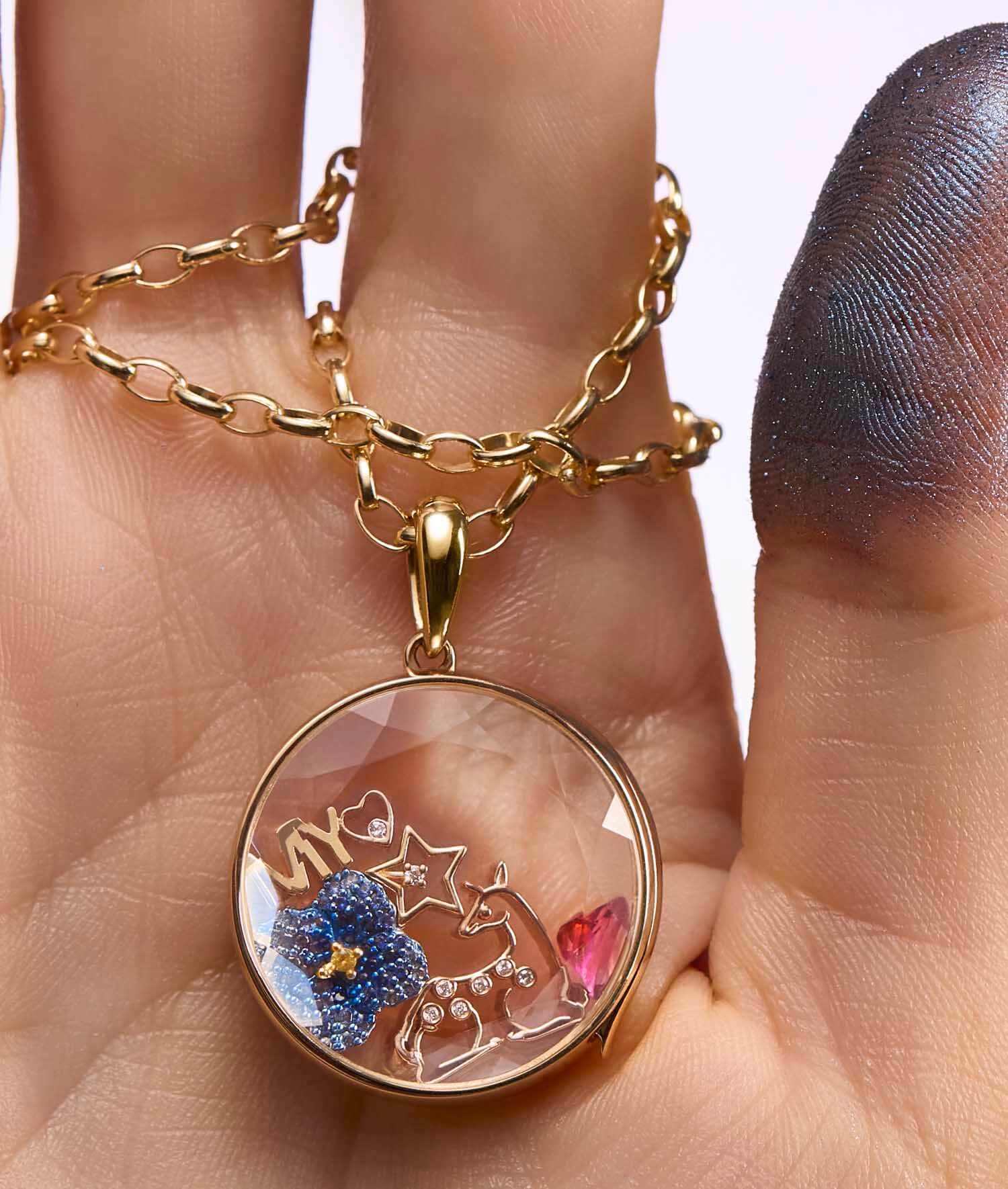 Elegant 18k gold deer spirit animal charm with diamond, featuring a forest locket design, held in a hand for a touch of nature's calm.