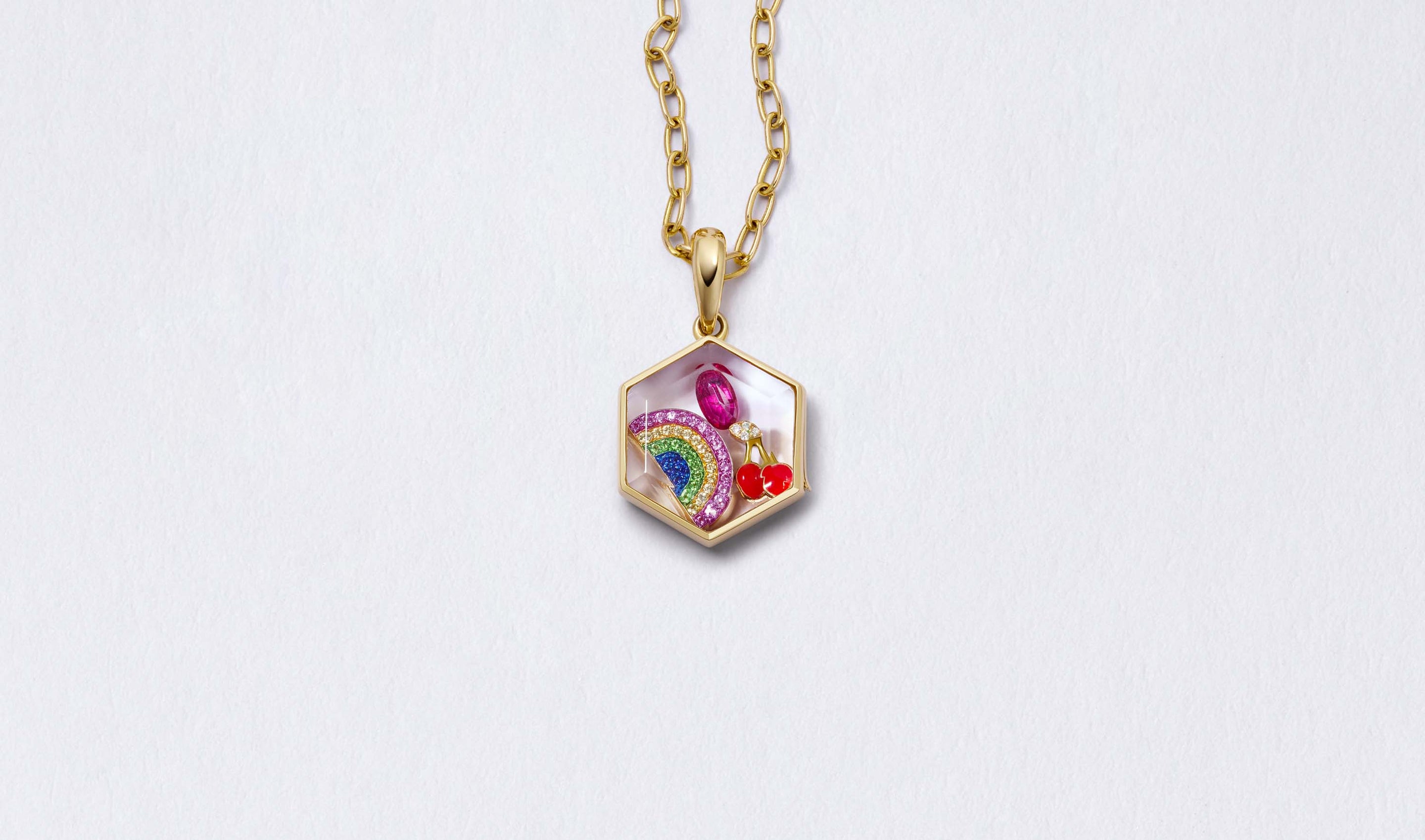 Honeycomb Gold Locket 14k personalised with colourful solid 18k gold charms and hanging on a yellow gold chain photographed on a neutral background.