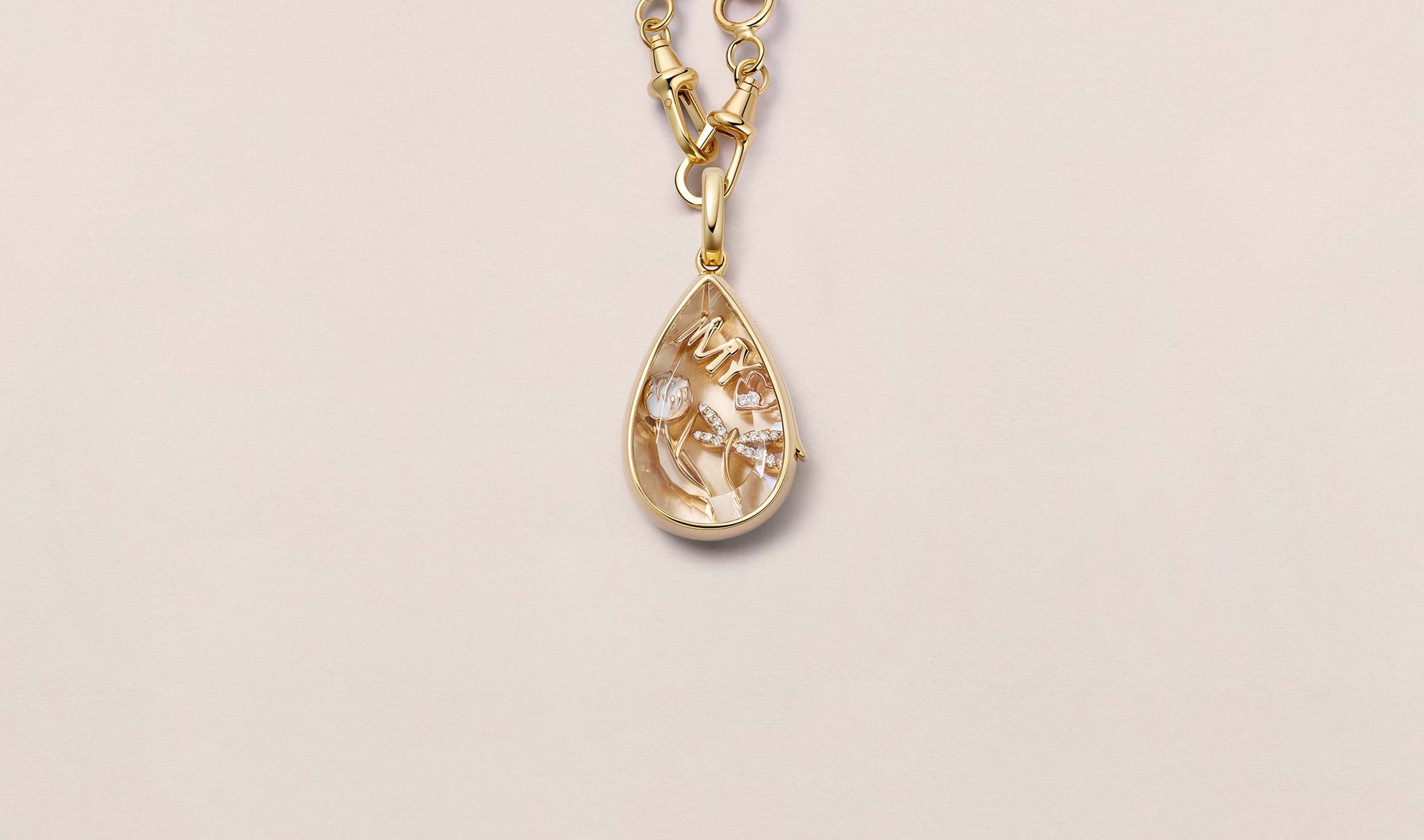 Lacrima Teardrop Gold Locket 14k  personalised with colourful solid 18k gold charms and hanging on a yellow gold chain photographed on a neutral background.