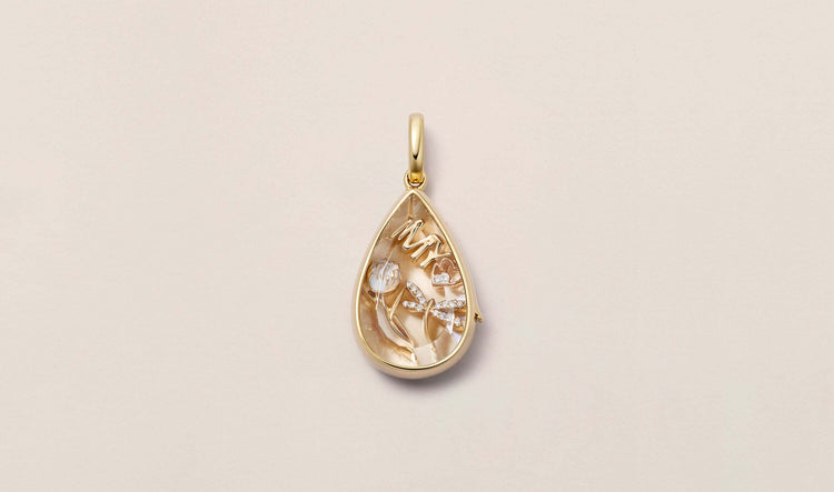Our teardrop lacrima locket pendant styled with our My Love 18k solid gold and set with a diamond with two other charms