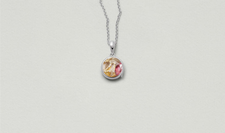 Mini Round White Gold Locket 14k  personalised with colourful solid 18k gold charms and hanging on a white gold chain photographed on a neutral background.