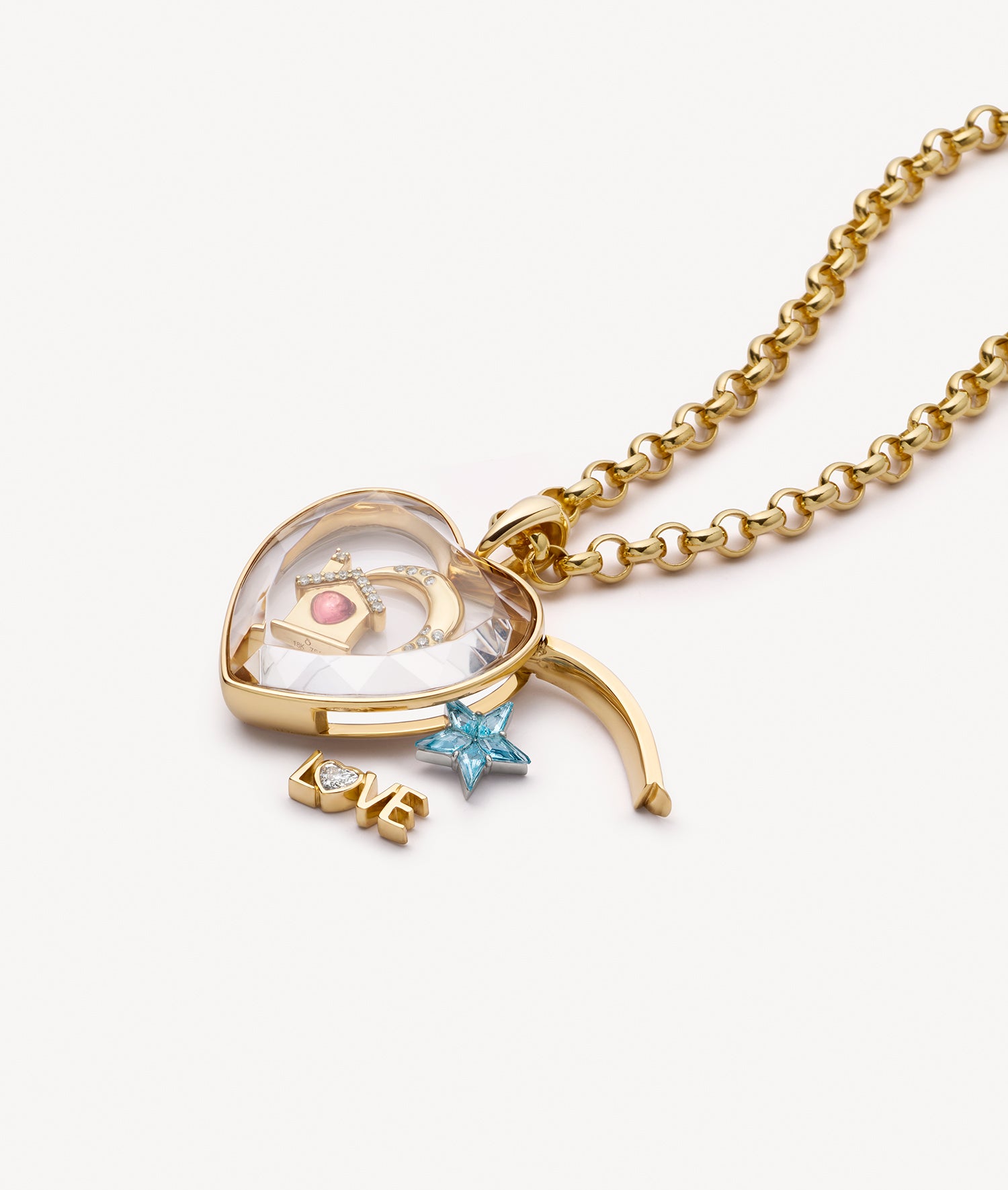 A gold heart-shaped pendant necklace with a crystal facade showing a miniature moon and star charms, a small blue star charm, and a dangling gold 'LOVE' text charm, on a white background.