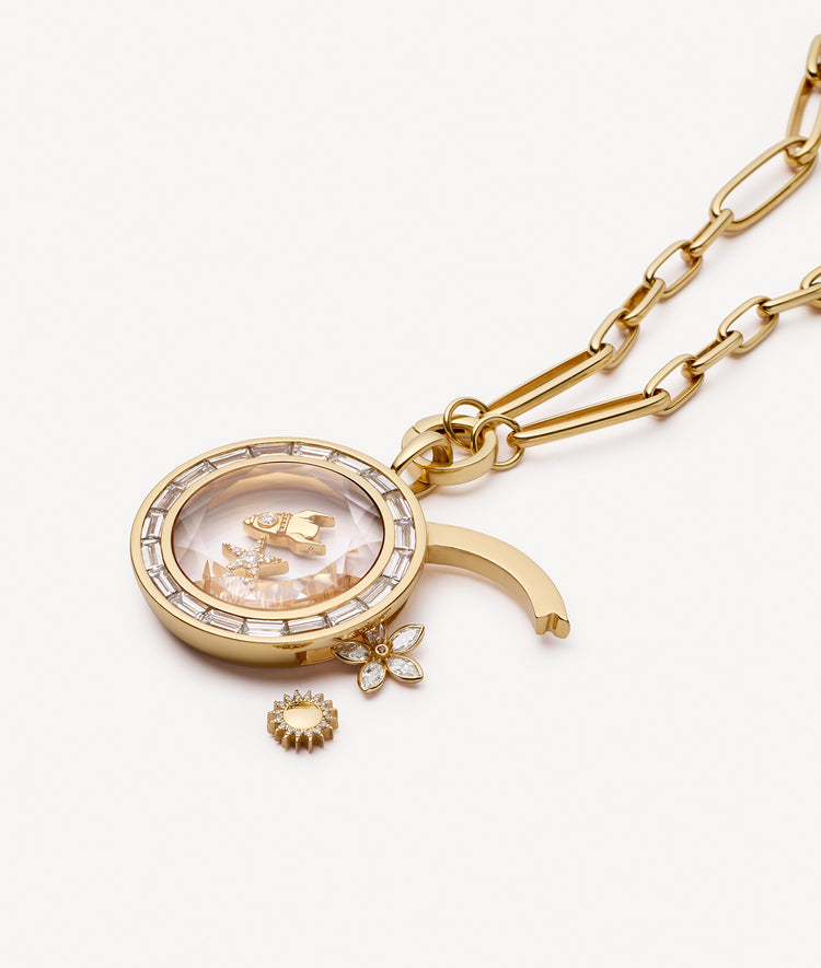 Gold locket pendant necklace with crystal facade styled with open latch with gold and diamond charms on a white background