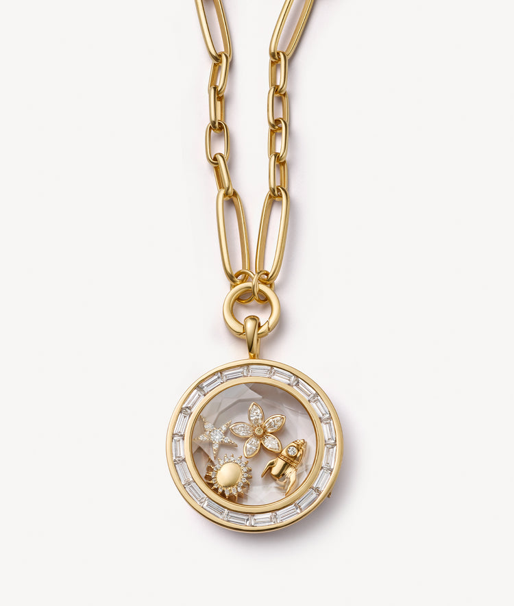 Gold locket pendant necklace with crystal facade styled with gold and diamond charms on a white background