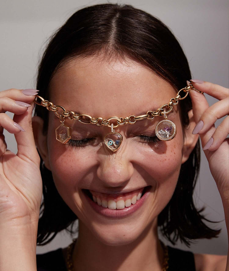 Pear cut gold locket, honeycomb locket, round loquet attached to chain styled across models face.