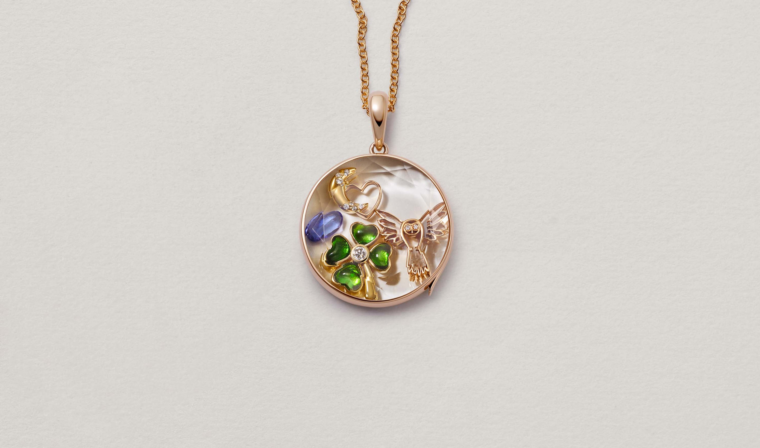 Large Round Rose Gold Locket 14k personalised with colourful solid 18k gold charms and hanging on a rose gold chain photographed on a neutral background.