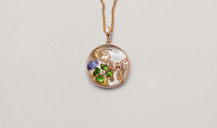 Large Round Rose Gold Locket 14k personalised with colourful solid 18k gold charms and hanging on a rose gold chain photographed on a neutral background.